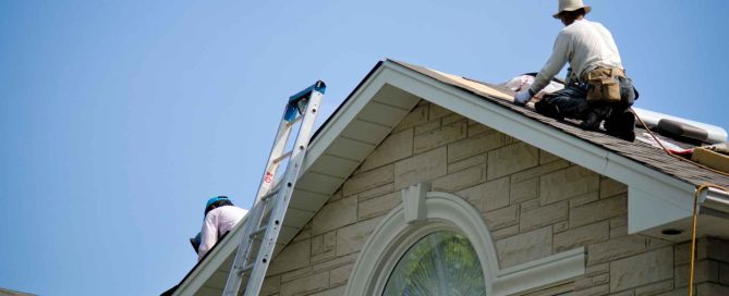 Two professional roofing contractors inspecting and fixing a roof structure.