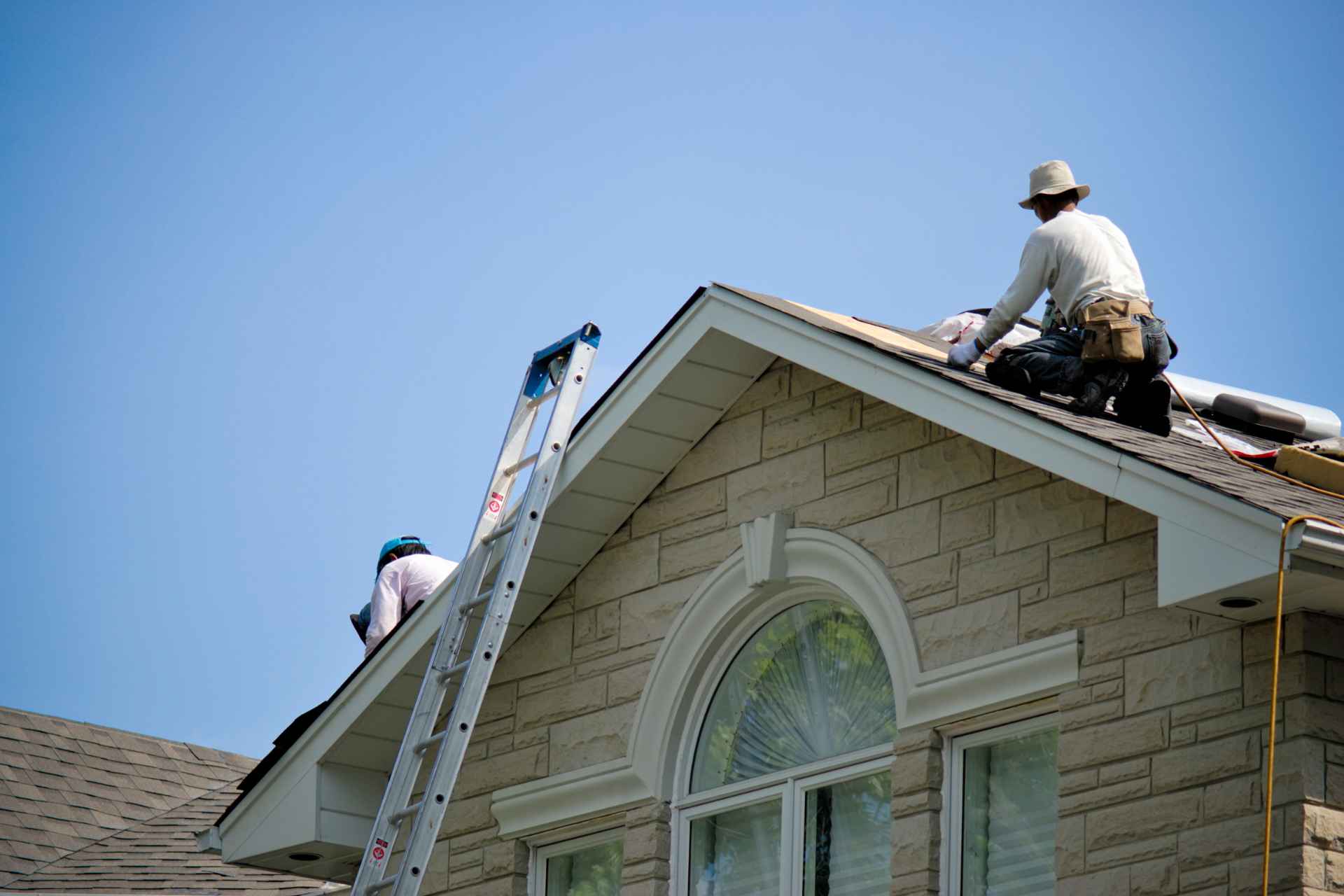 Two professional roofing contractors inspecting and fixing a roof structure.