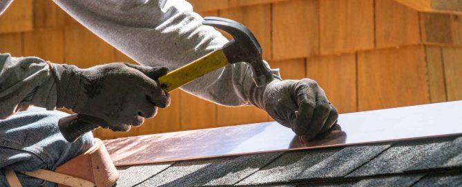 Close-up of a professional installer securing metal roof flashing along a residential roof seam.